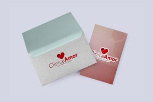 Envelope cinza com aba verde-clara e logo Clínica Amor ao lado de uma peça rosa com a mesma marca