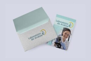 Envelope cinza com aba verde-clara e logo Laboratório de Análise ao lado de material com foto de profissional
